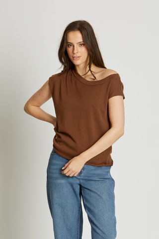 Woman wearing a brown top and blue jeans on a white background