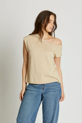 Woman wearing a beige top and blue jeans on a white background