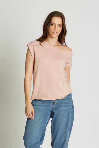 Woman wearing a light pink sleeveless top and blue jeans on a white background